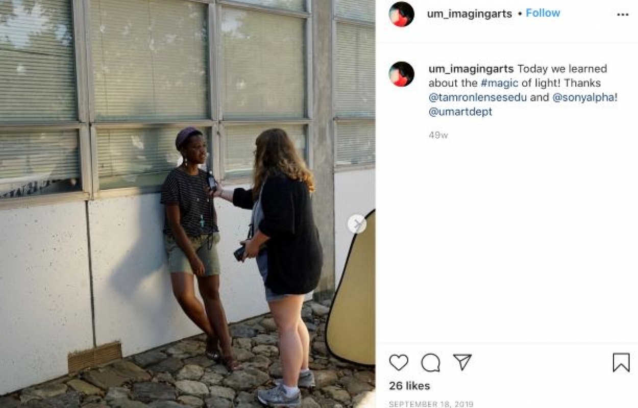 Clicks Instagram post featuring one student posing while the other takes her image. They are learning how to work with light.