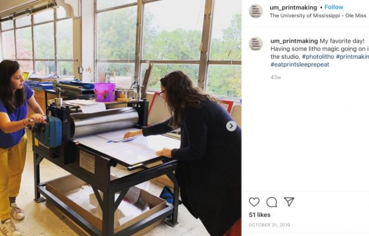 Printmaking Instagram post featuring two students rolling out a print.