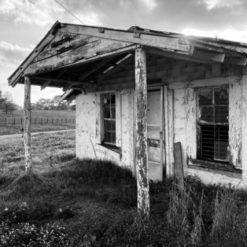 black and white photography of a run-down rural house