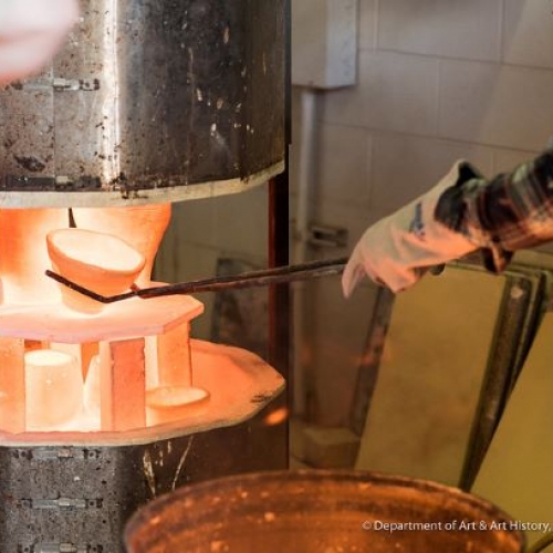 Person removing a glowing hot ceramic bowl from a kiln