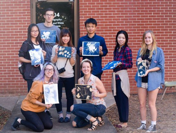 A group of students standing together showing their nature-inspired work after a photography workshop