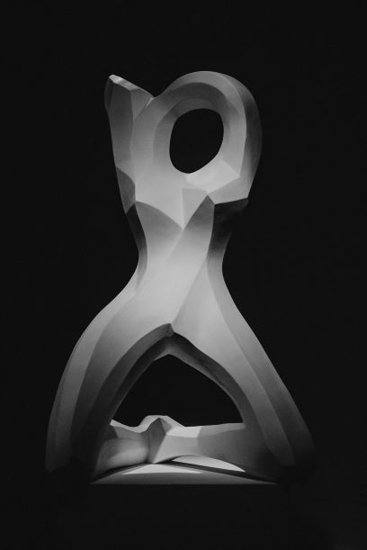 photo of white sculpture against black background. sculpture resembles a human form