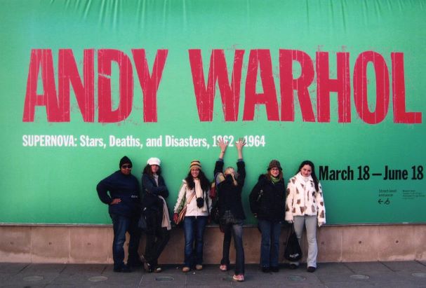 art history students standing in front of a banner for an Andy Warhol exhibit in Chicago.