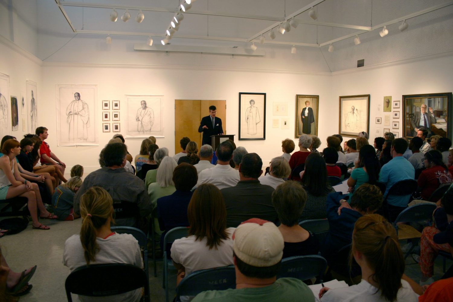 An artist gives a talk to a large crowd in the department's gallery.