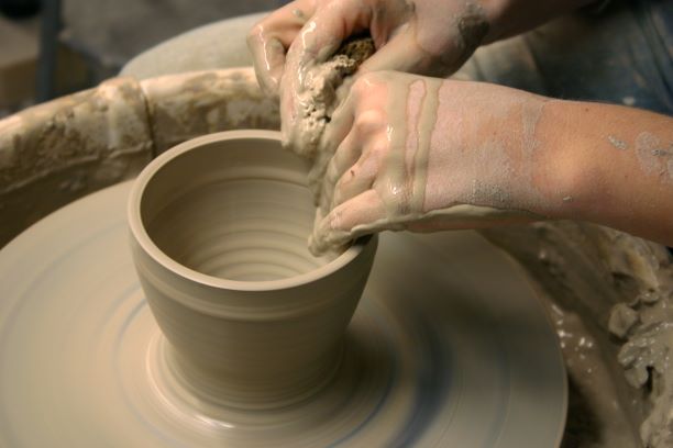 close-up photo of hands creating a bowl on a pottery wheel
