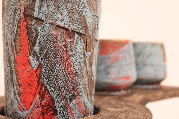 A ceramic piece with rough texture and colors of red, gray, and brown