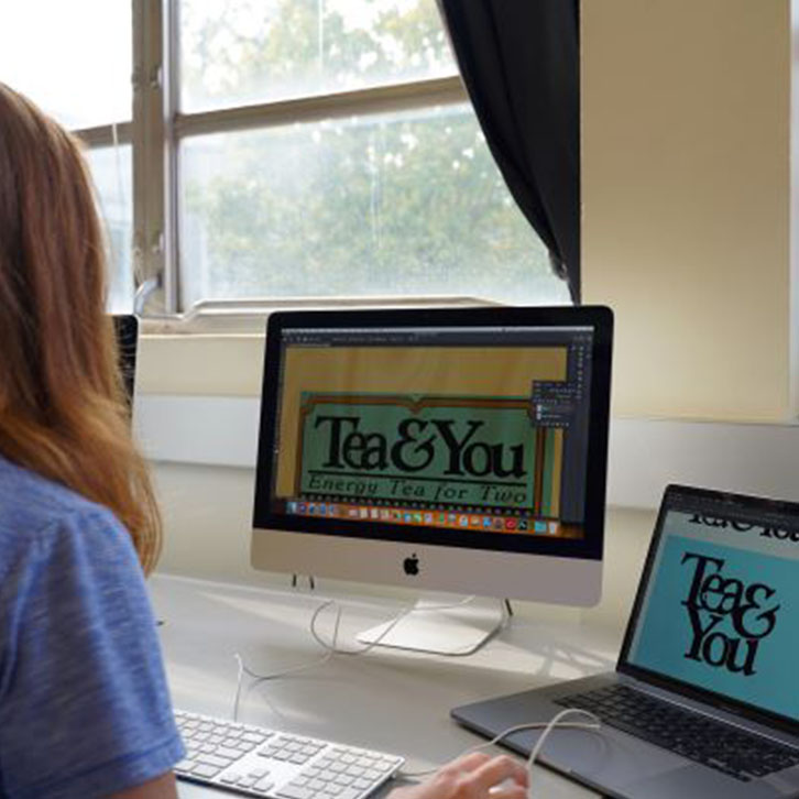 A student works on a design for a tea label at a computer station