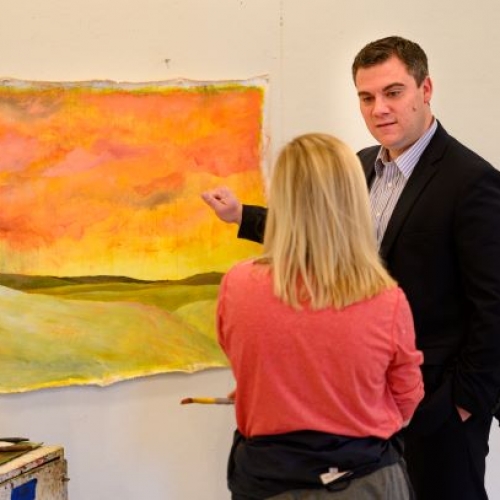 Professor Jackson consults with a painting student with her abstract painting on the wall.