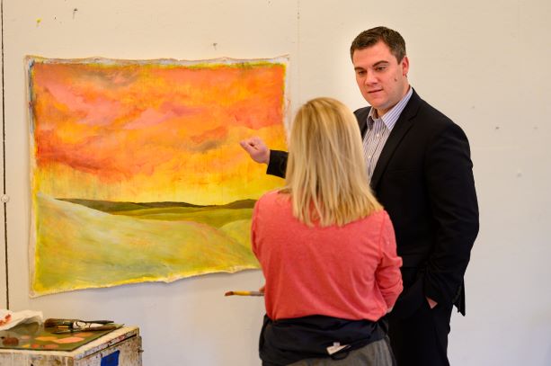 Professor Jackson consults with a painting student with her abstract painting on the wall.