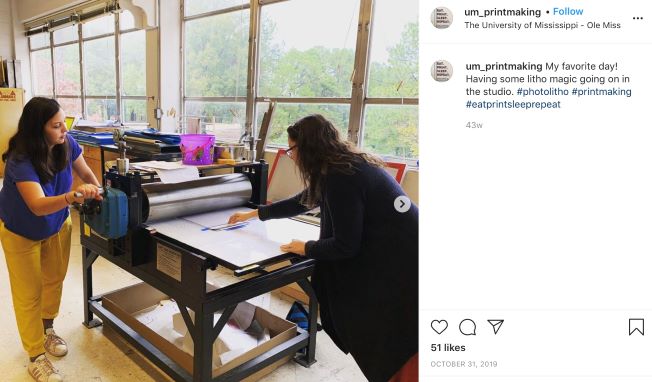 Printmaking Instagram post featuring two students rolling out a print.